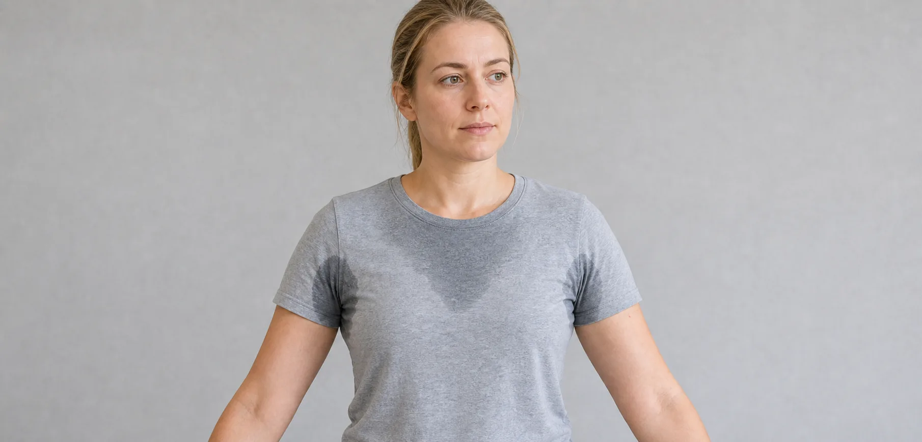 Adult in a grey shirt showing the clothing area affected by underarm sweating