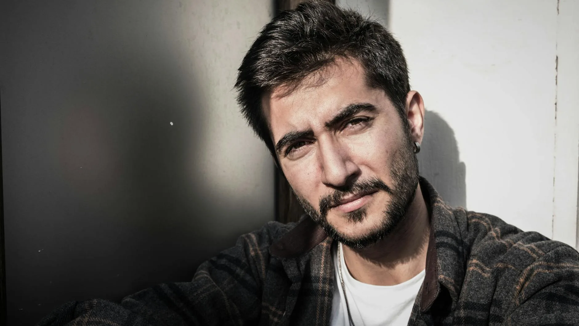 Close smartphone-style portrait of a bearded adult man in strong side light