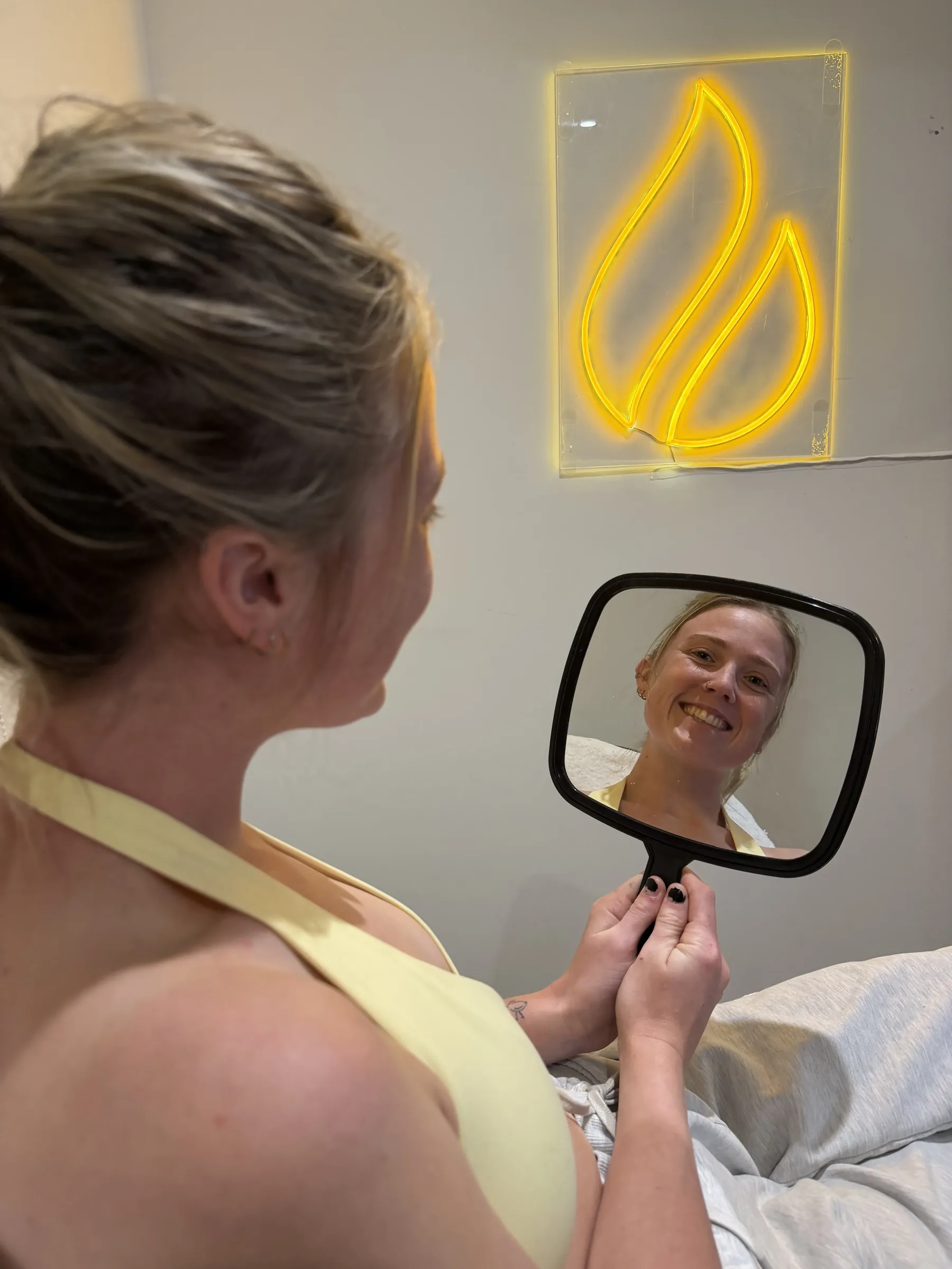 Adult patient using a handheld mirror during first wrinkle consultation planning at Core Aesthetics