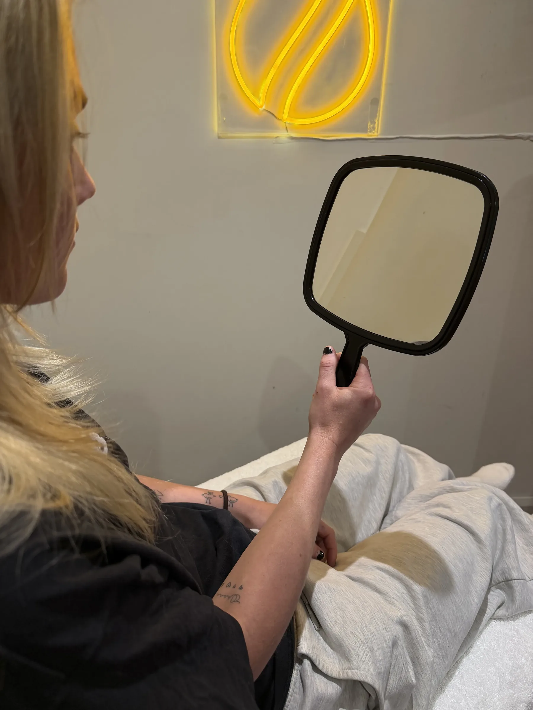 Adult woman holding a blank mirror during a consultation at Core Aesthetics