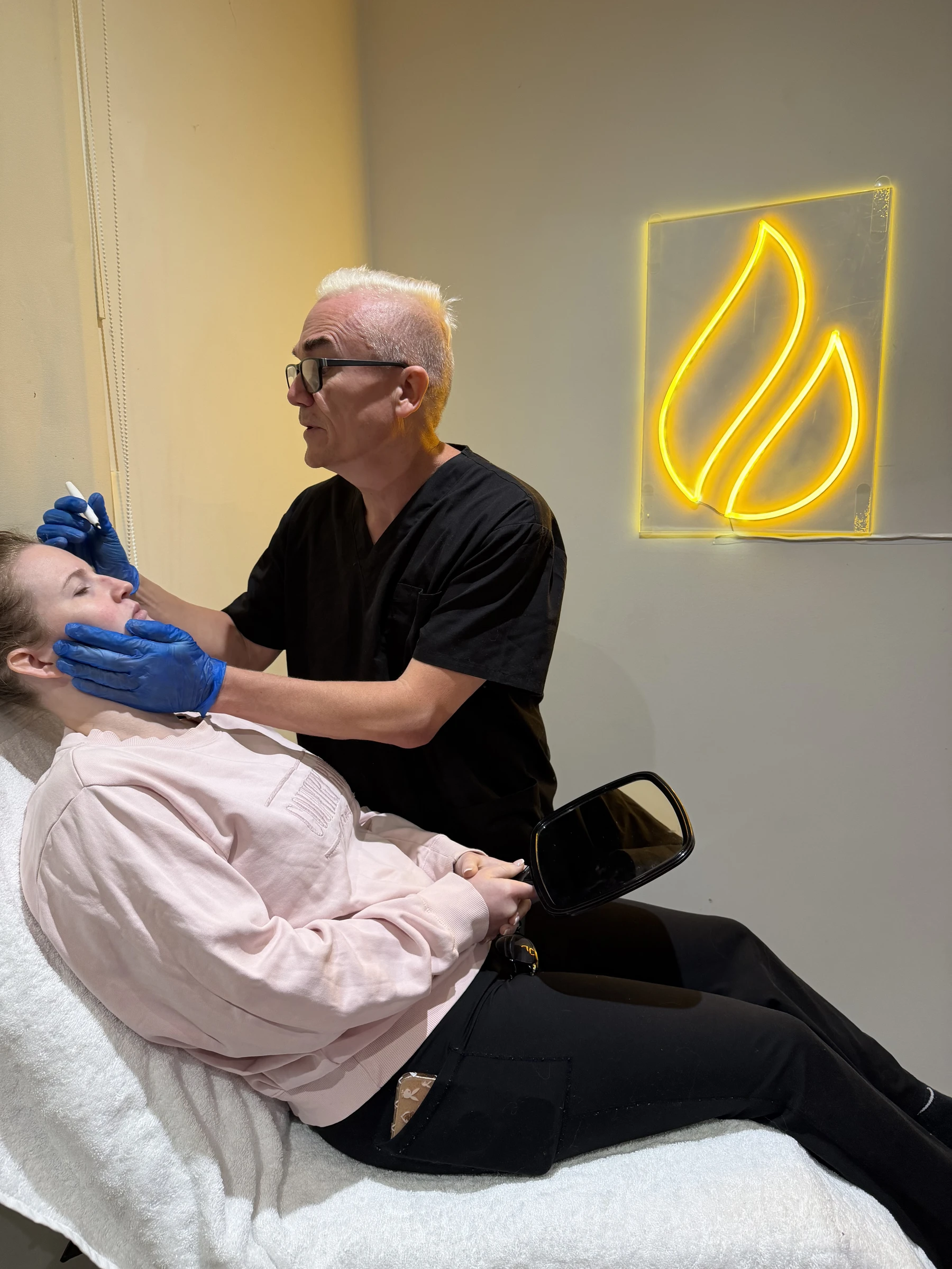 Corey Anderson RN assessing an adult patient's lower face and jaw muscle area at Core Aesthetics Oakleigh