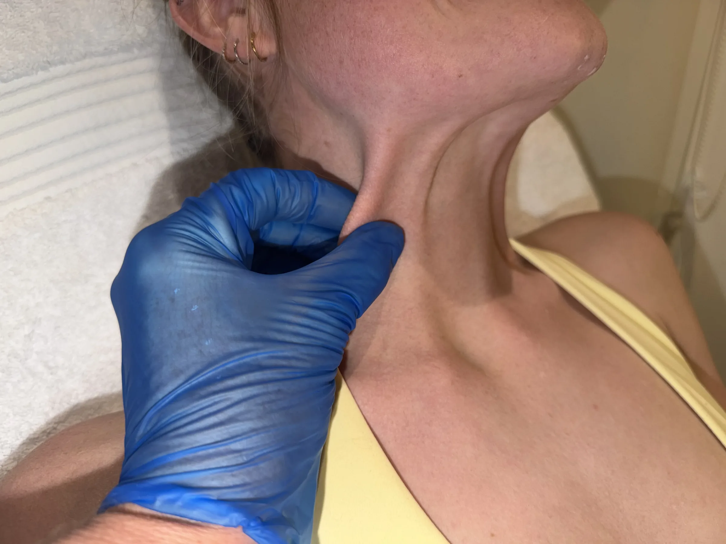 Corey Anderson RN assessing the front and side of an adult staff model's neck in the Oakleigh clinic