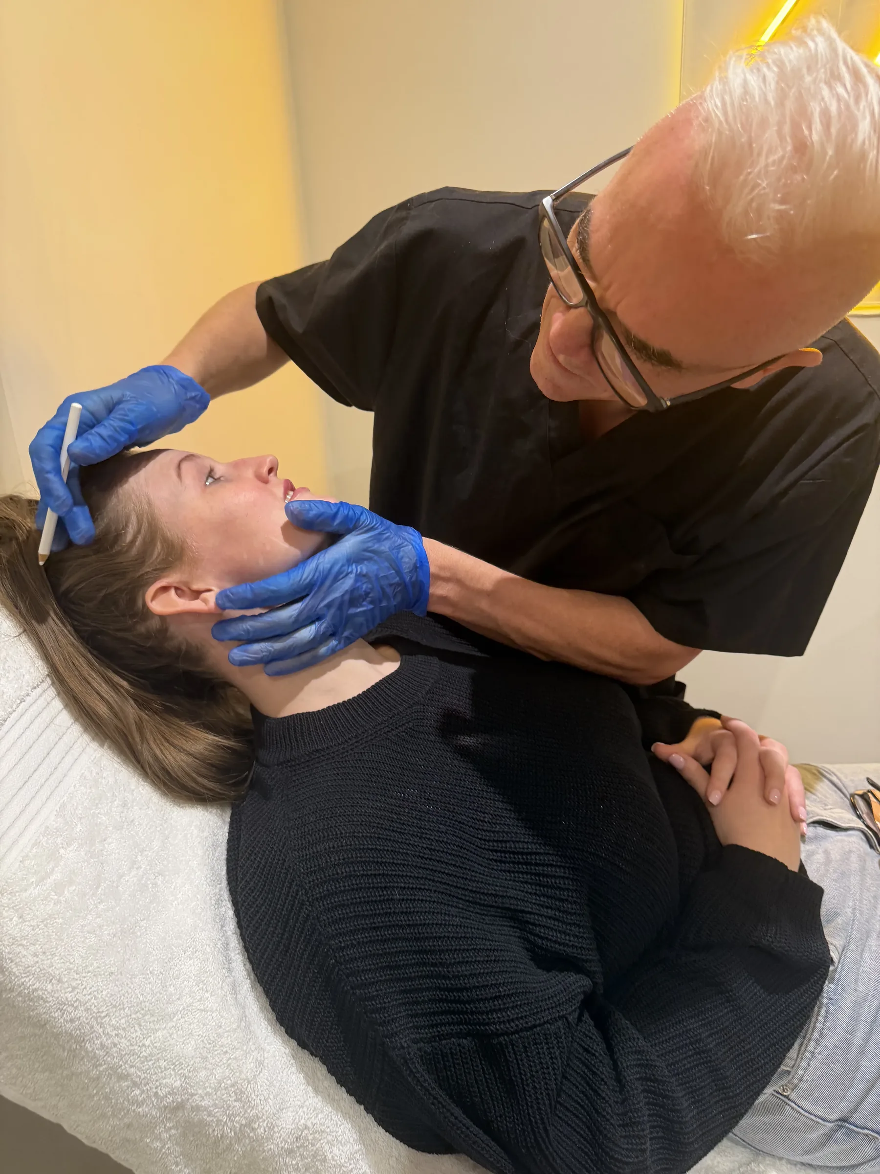 Corey Anderson RN observing lower-face and neck movement with an adult staff model in the Oakleigh clinic