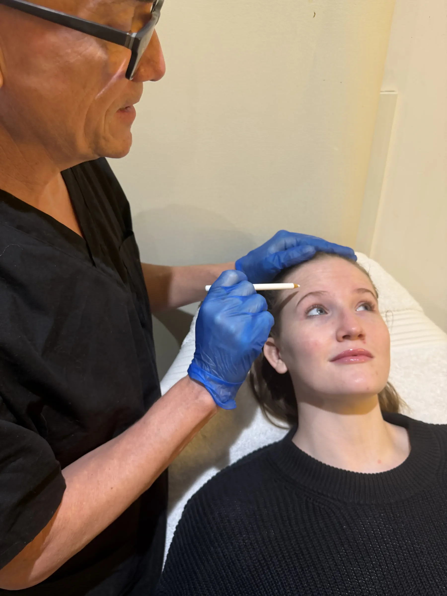 Corey Anderson RN observing brow position while an adult female staff model looks upward during an upper-face assessment