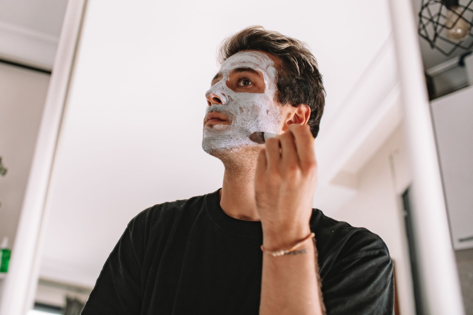 Man following a personal grooming routine in a bathroom setting.