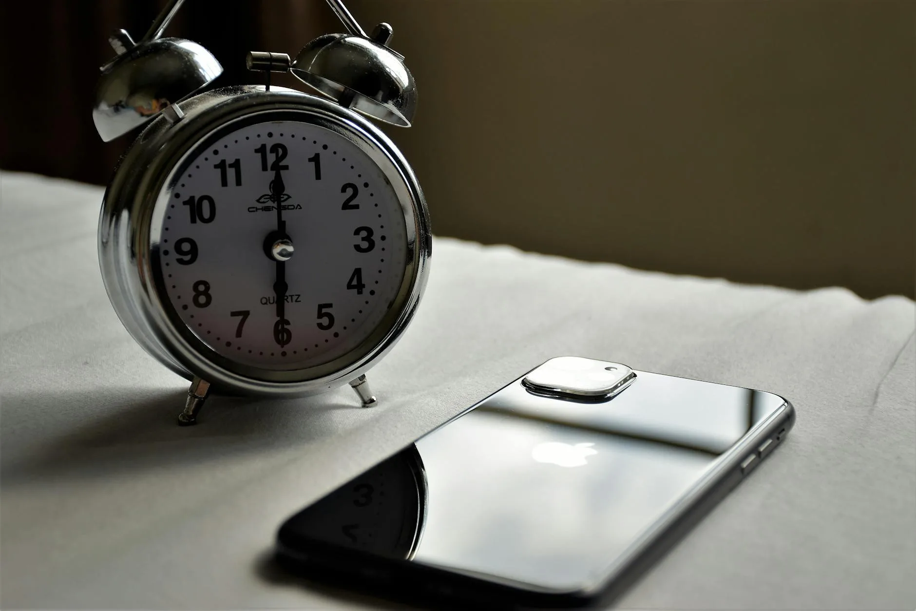 Phone lying beside an alarm clock.