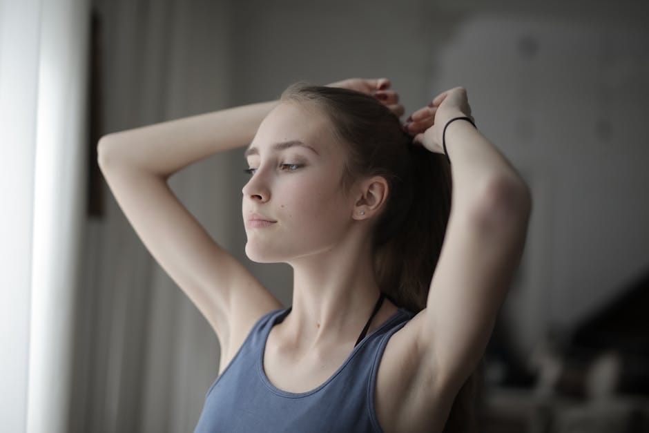 Adult woman lifting her hair with both arms, showing the upper shoulder and neck line in natural movement
