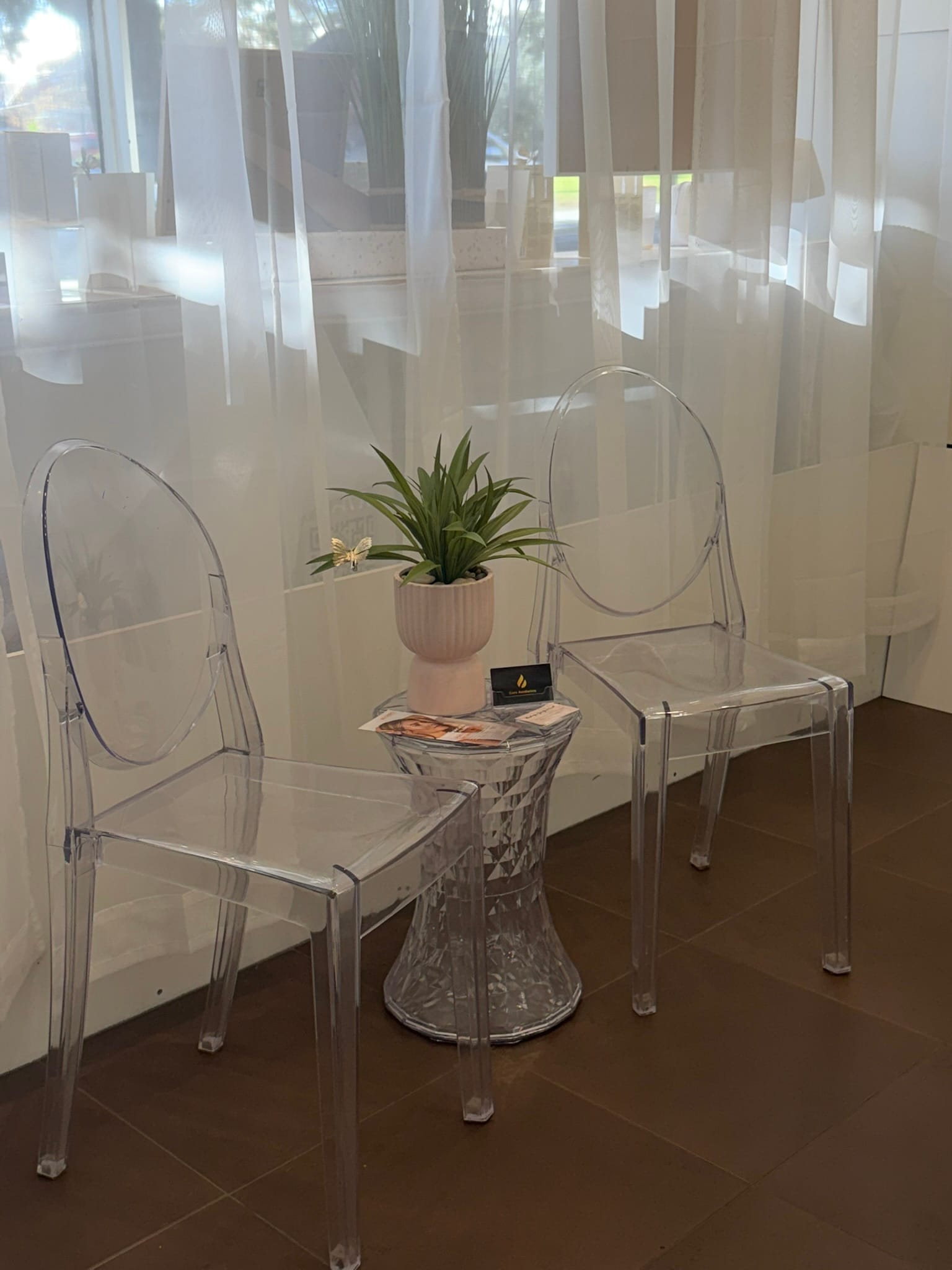 Two clear acrylic chairs beside a small table in the Core Aesthetics waiting area