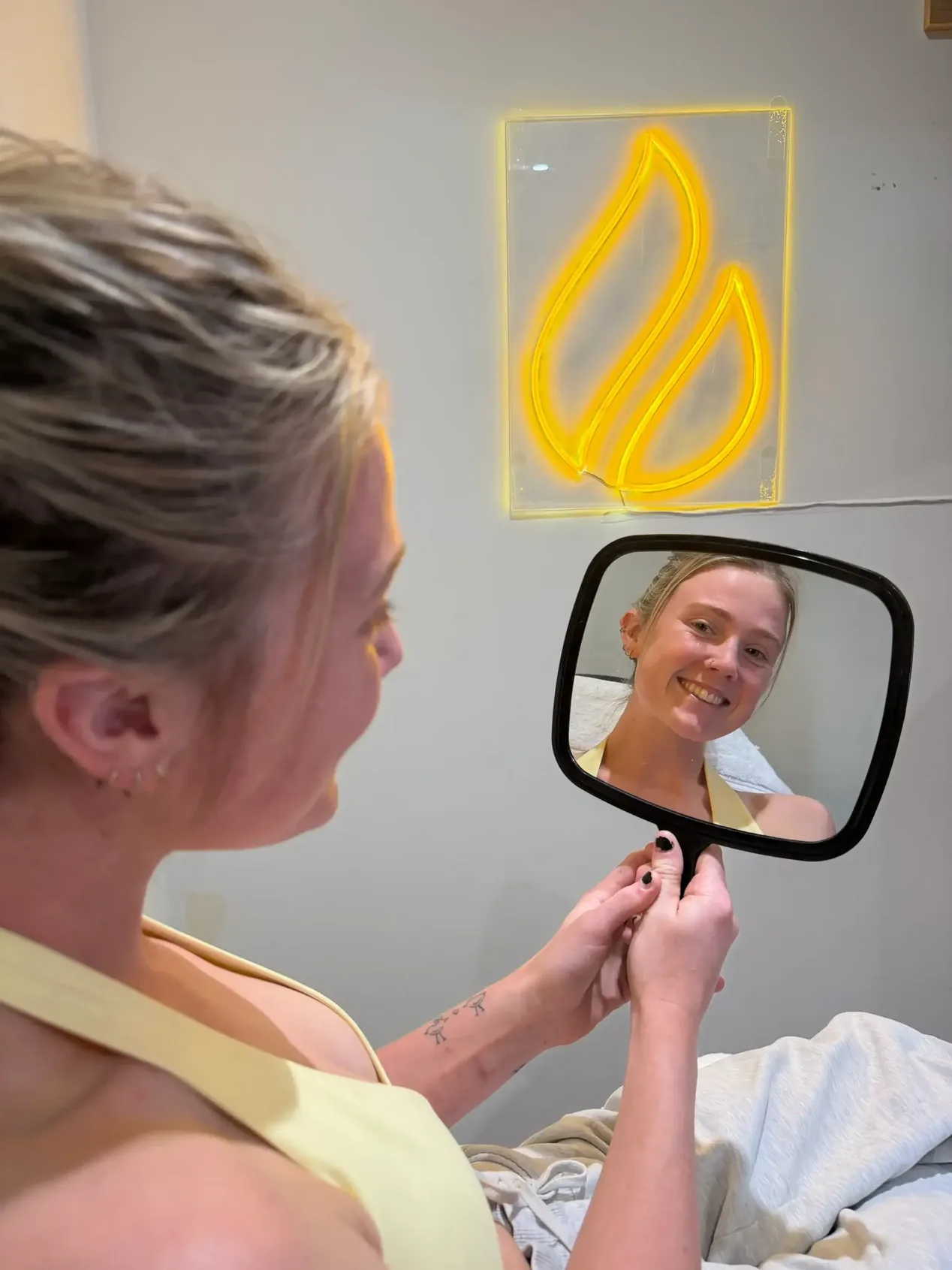 Adult woman using a hand mirror to describe what she notices before a consultation