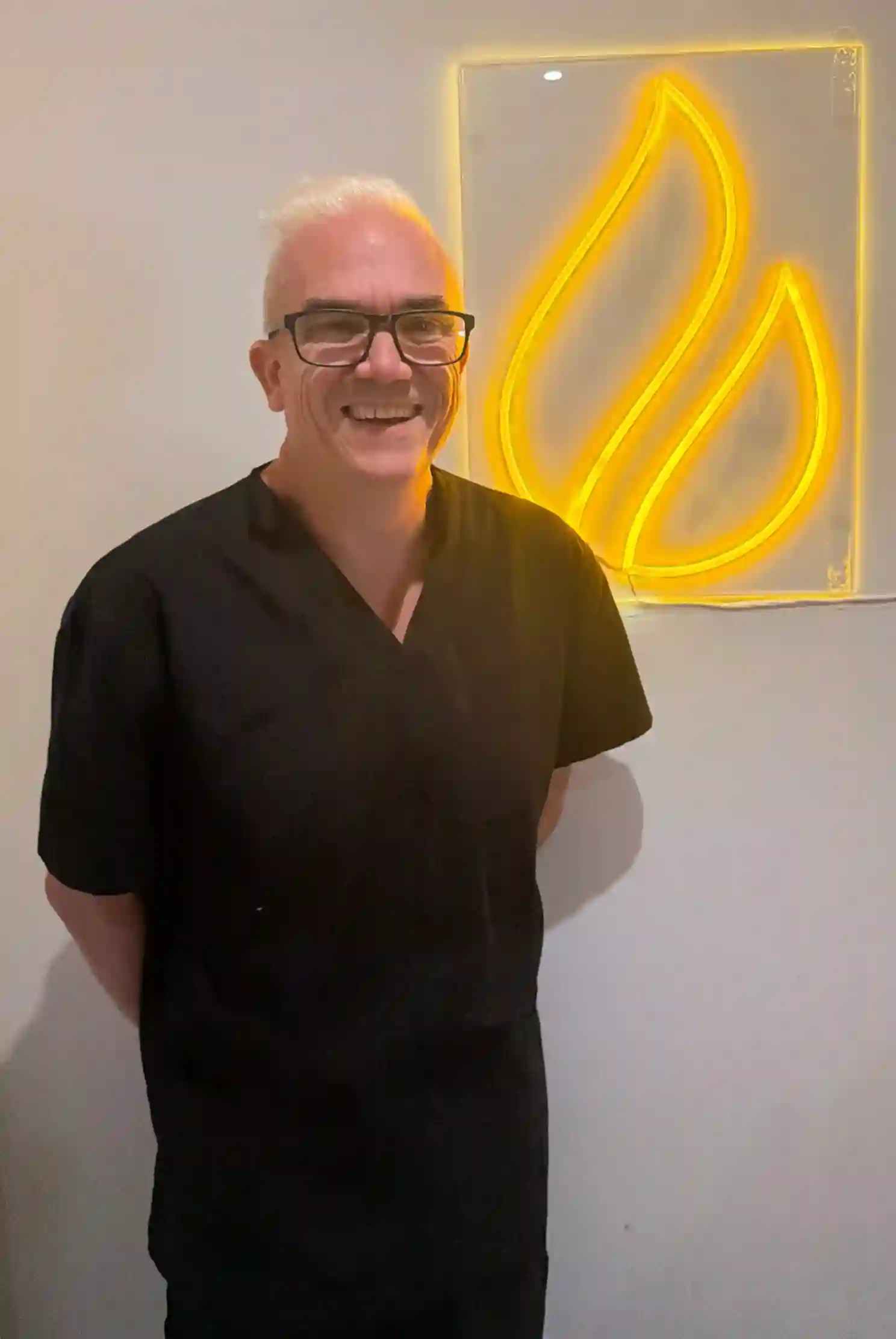 Corey Anderson RN beside the illuminated Core Aesthetics sign in Oakleigh